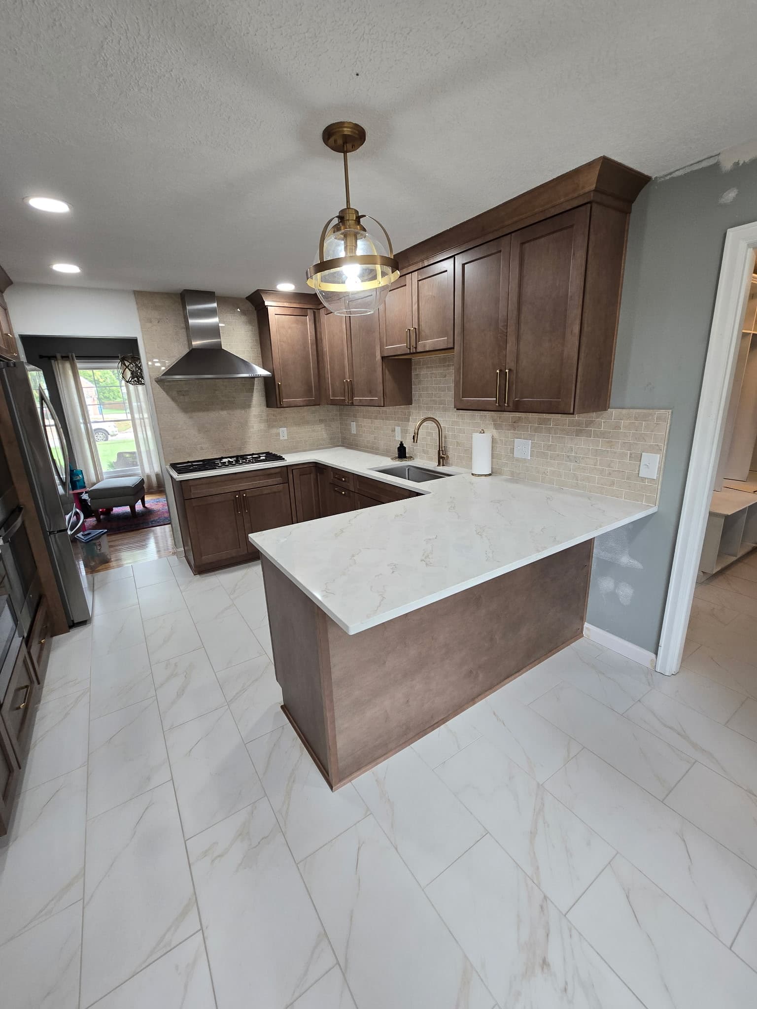 Walnut shaker kitchen remodel with marble quartz peninsula and brass pendant by 8 Is Enough Construction in Lorain County OH